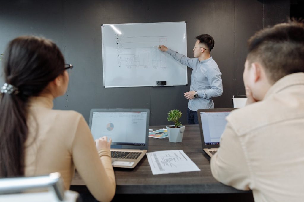 man-in-blue-long-sleeve-shirt-presenting-in-a-meeting-7653999 Business team discussing project strategy during a meeting in a modern office.