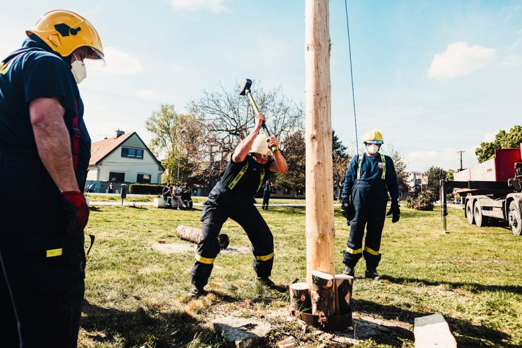 man-in-uniform-hammering-the-wood-log-of-a-pole-7812844 Firefighters using sledgehammers in an outdoor lumberjack demonstration with wooden pole.